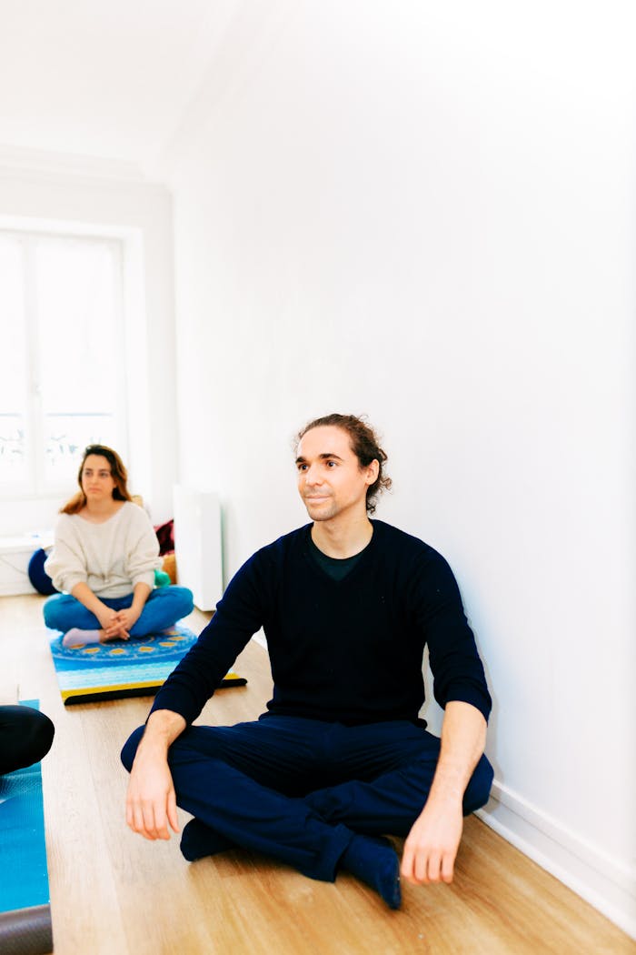 People practicing yoga and meditation in a bright indoor space, promoting relaxation and mindfulness.