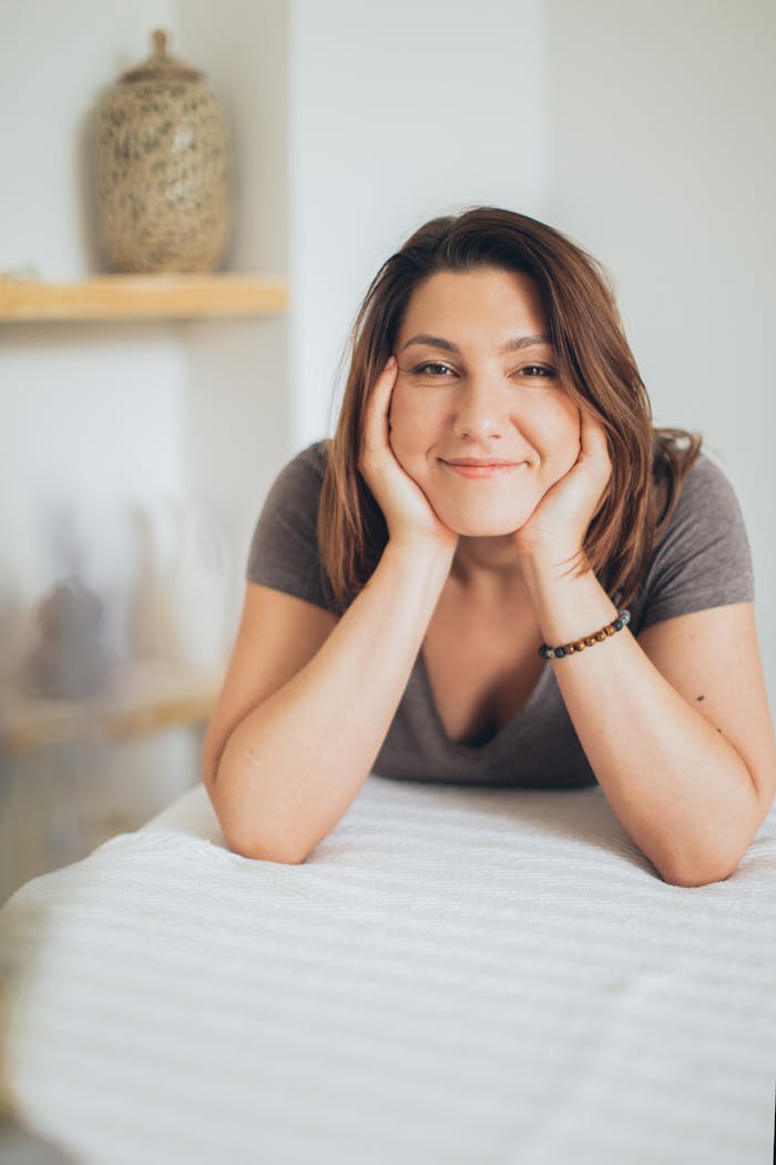 Woman smiling indoors, enjoying a relaxing spa day with a happy expression.